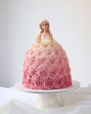 Barbie doll cake with pink and white frosting on a white background