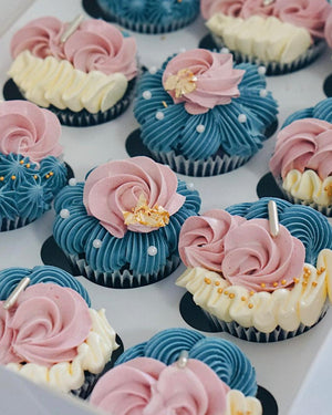 Decorative cupcakes with pink, blue, and white frosting on a white surface.