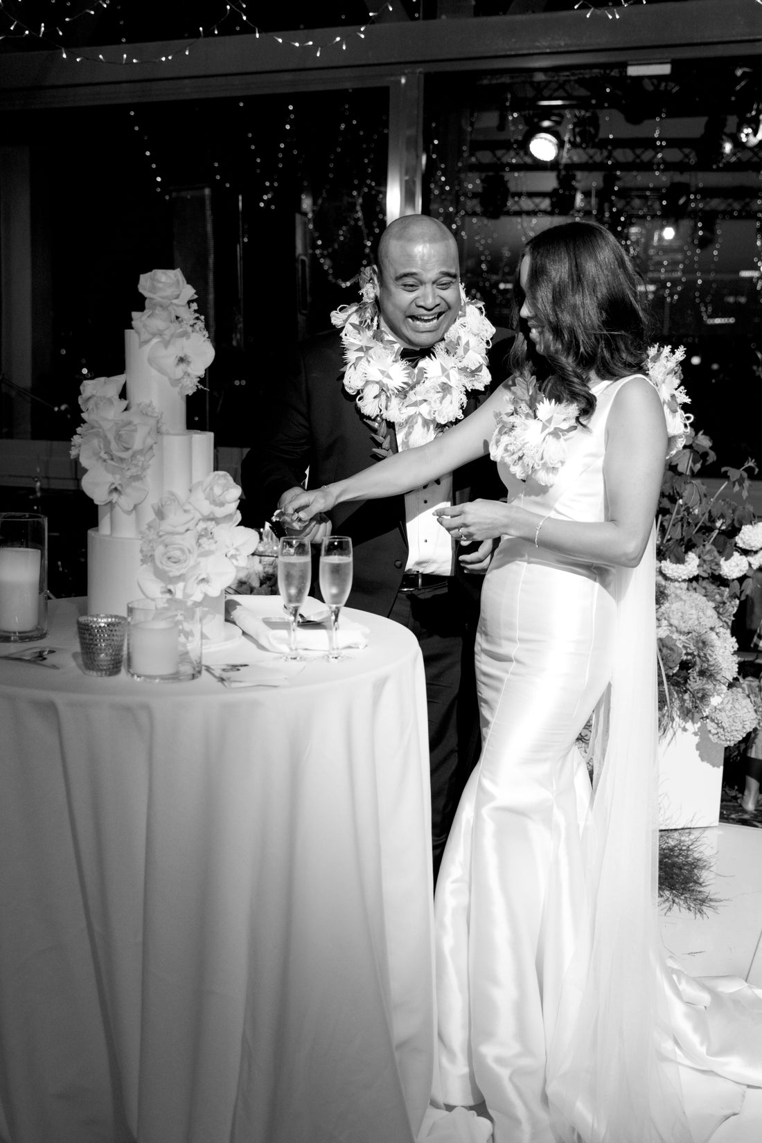 Black and white photo of a couple at a wedding reception with a cake.
