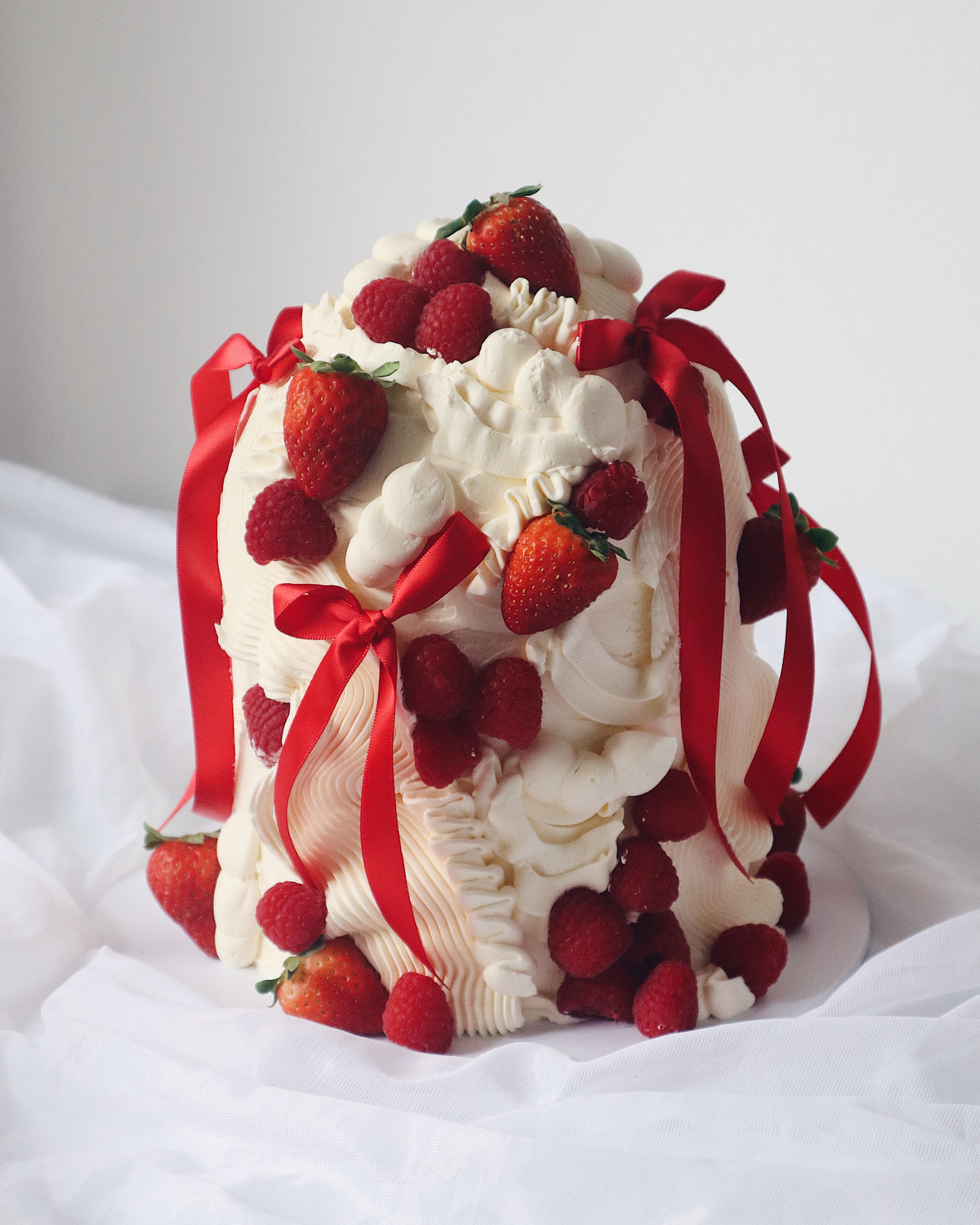 Decorative cake with strawberries and red ribbons on a white background