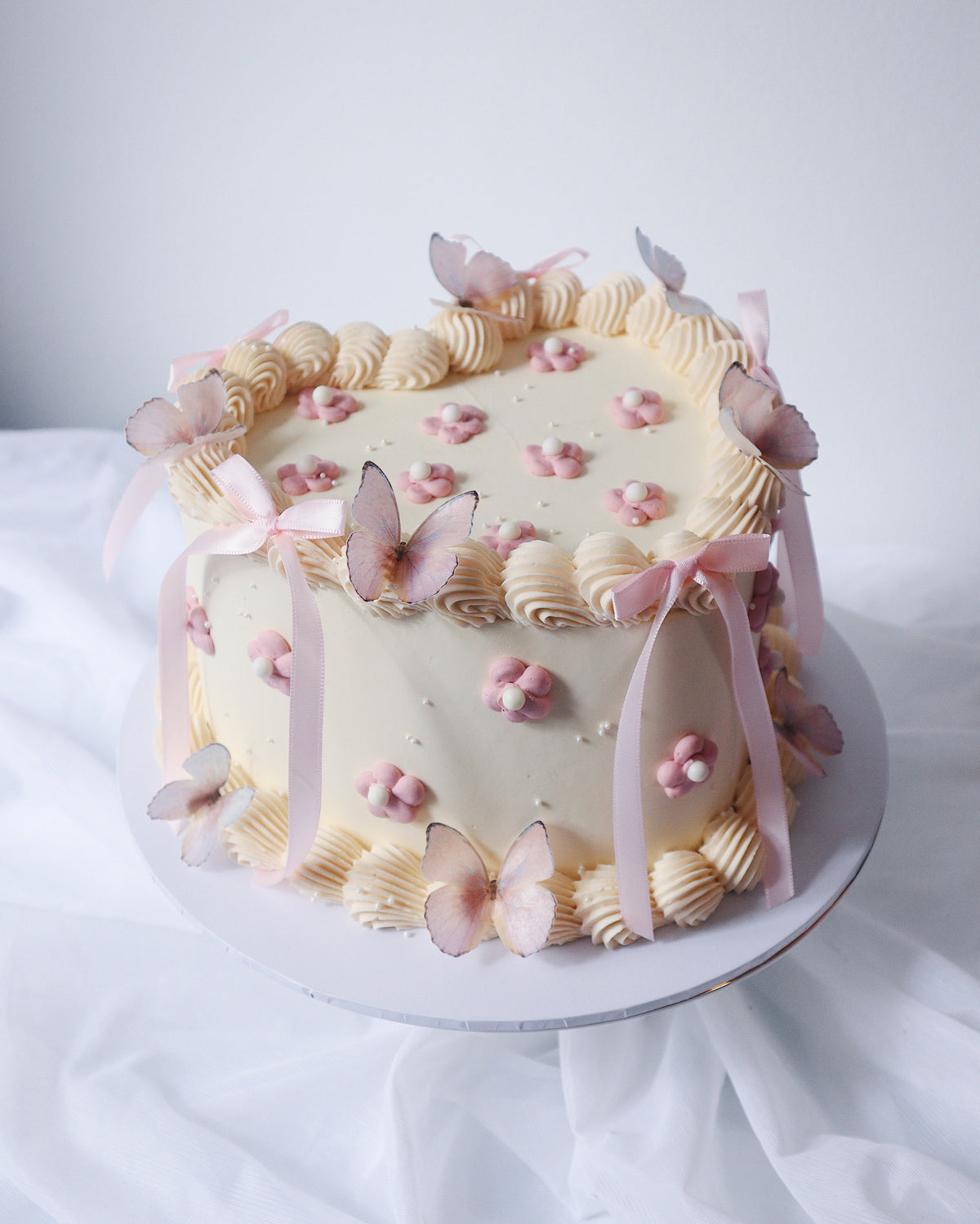 Decorative cake with pink flowers and butterfly decorations on a white background