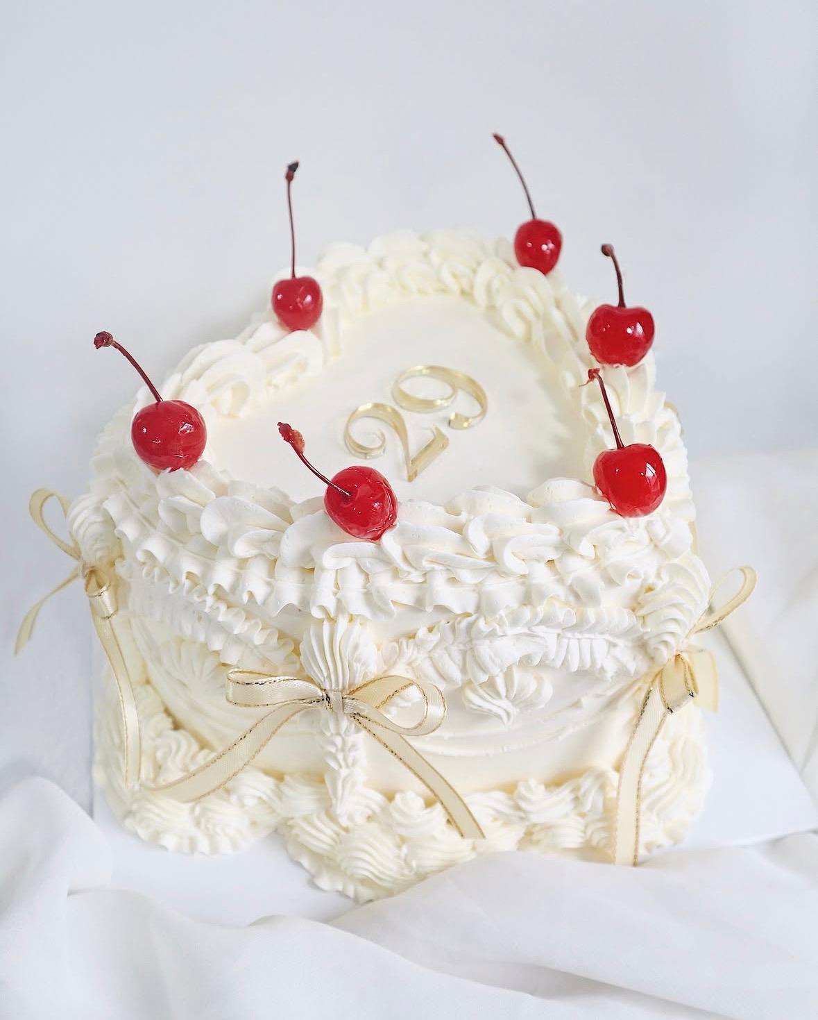 White cake with red cherries on top against a white background