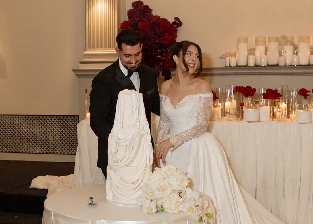 Couple cutting a wedding cake in a decorated room with candles and flowers.