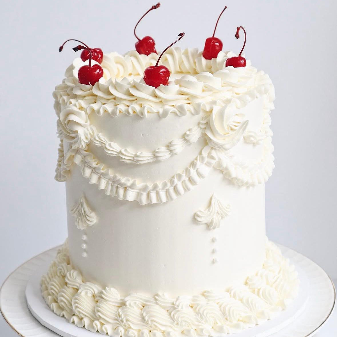White cake with white frosting and red cherries on a white background