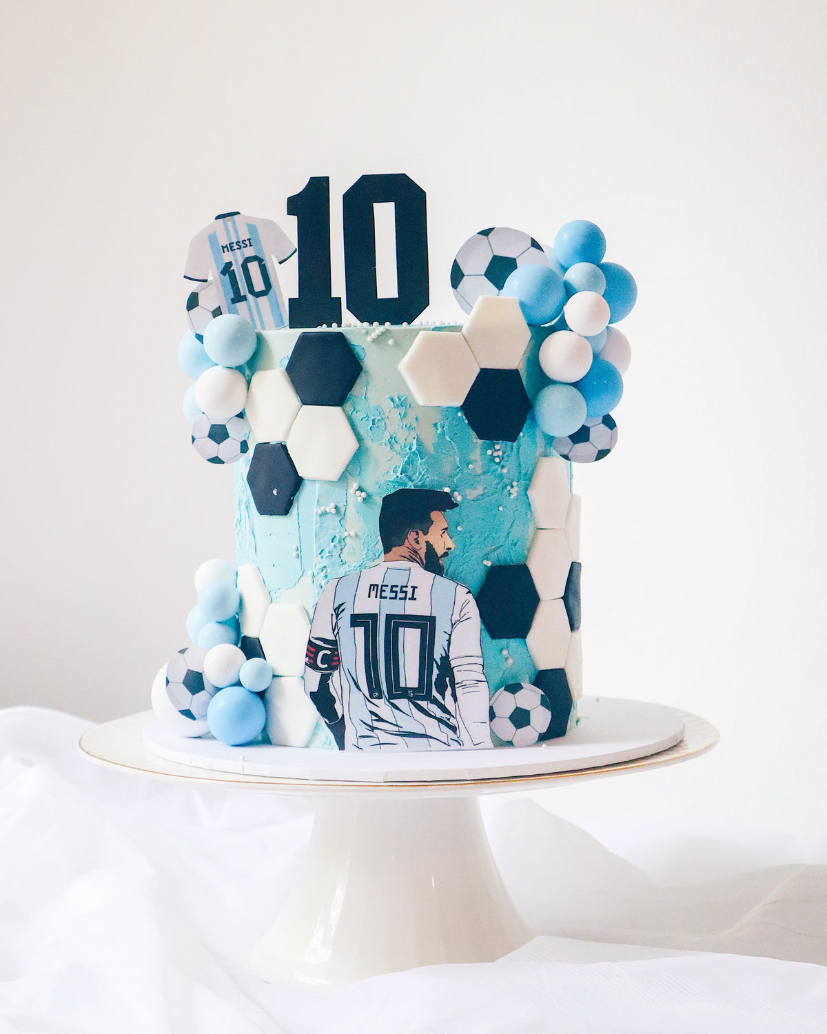Decorative cake with soccer ball design and number 10, featuring a person wearing a sports jersey.